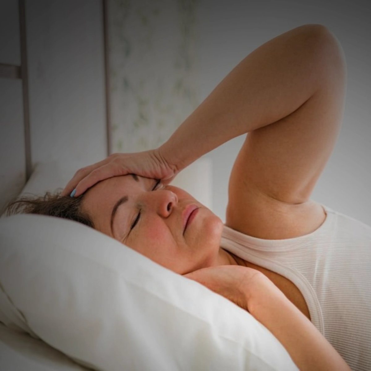 Femme réveillée par une douleur, la main sur le front